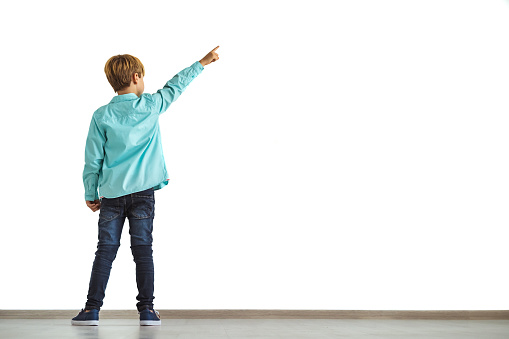 The little boy gesturing on the white wall background