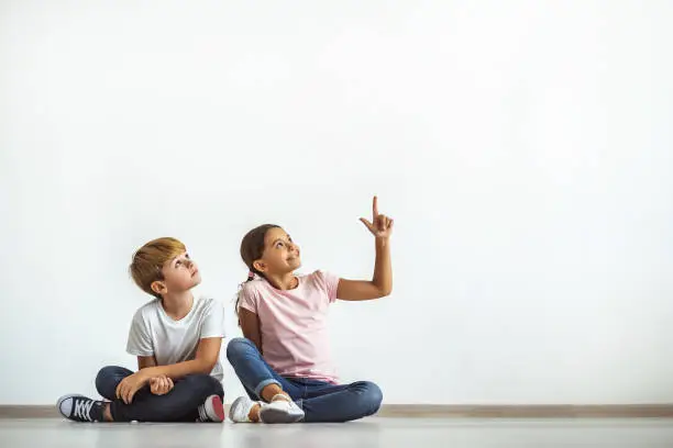 Photo of The happy girl and a boy sitting on the floor and gesturing