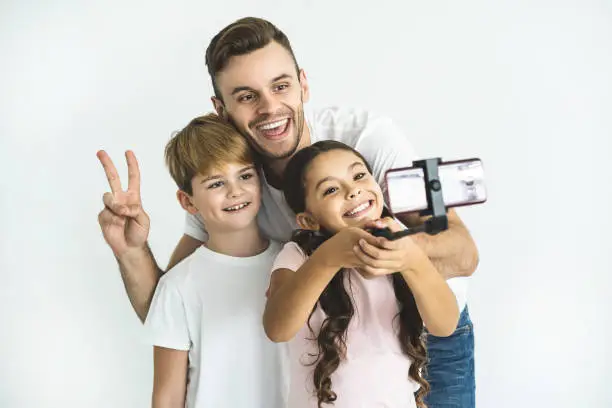 Photo of The happy father and children take selfie on the white background