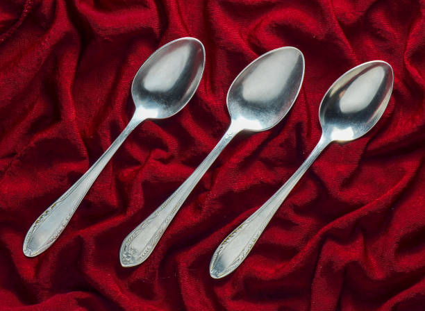istock A set of three metal spoons on a red silk tablecloth. Top view 1060219516