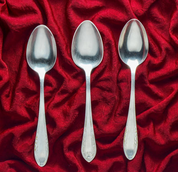 istock A set of three metal spoons on a red silk tablecloth. Top view. 1060219550