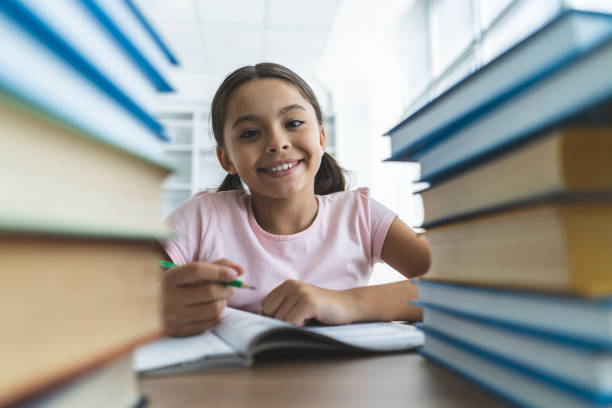 istock The happy girl sitting at the table with books and writing 1060220310