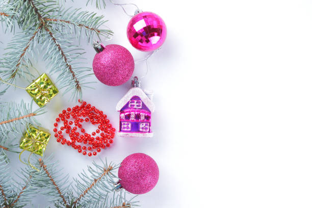 istock Christmas decorations. Spruce branches and holiday decorations on white background. Pink balls and toy house. Red necklace and golden boxes for festive Christmas tree 1060231624