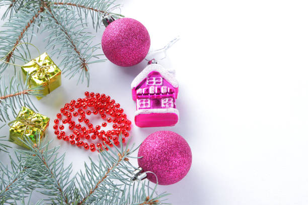 istock Christmas decorations. Spruce branches and holiday decorations on white background. Pink balls and toy house. Red necklace and golden boxes for festive Christmas tree 1060231646