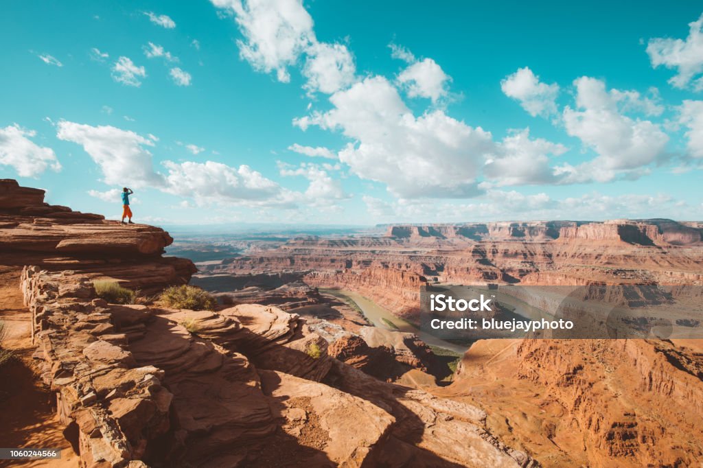 Hiker on a cliff in Dead Horse Point State Park, Utah, USA A young male hiker is standing on the edge of a cliff enjoying a dramatic overlook of the famous Colorado River and beautiful Canyonlands National Park in scenic Dead Horse Point State Park, Utah, USA Grand Canyon Stock Photo