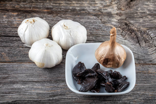 ail noir (ail fermenter noir) - garlic clove isolated white photos et images de collection