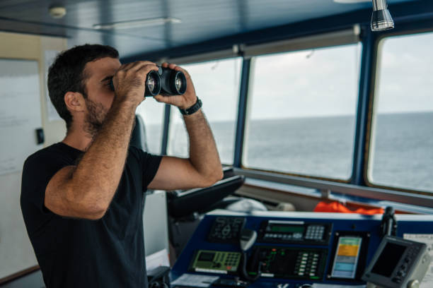 istock Navigational officer lookout on navigation watch looking through binoculars 1060254928