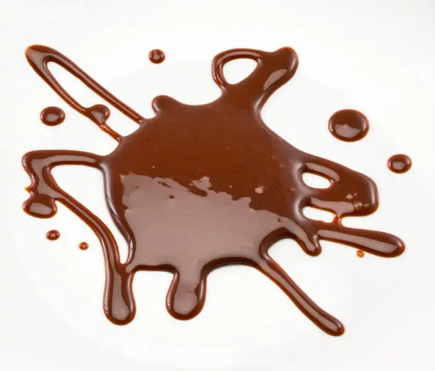 Chocolate syrup poured on a white surface. Studio photography. Cut out. High angle view. Indoors. Copy space.