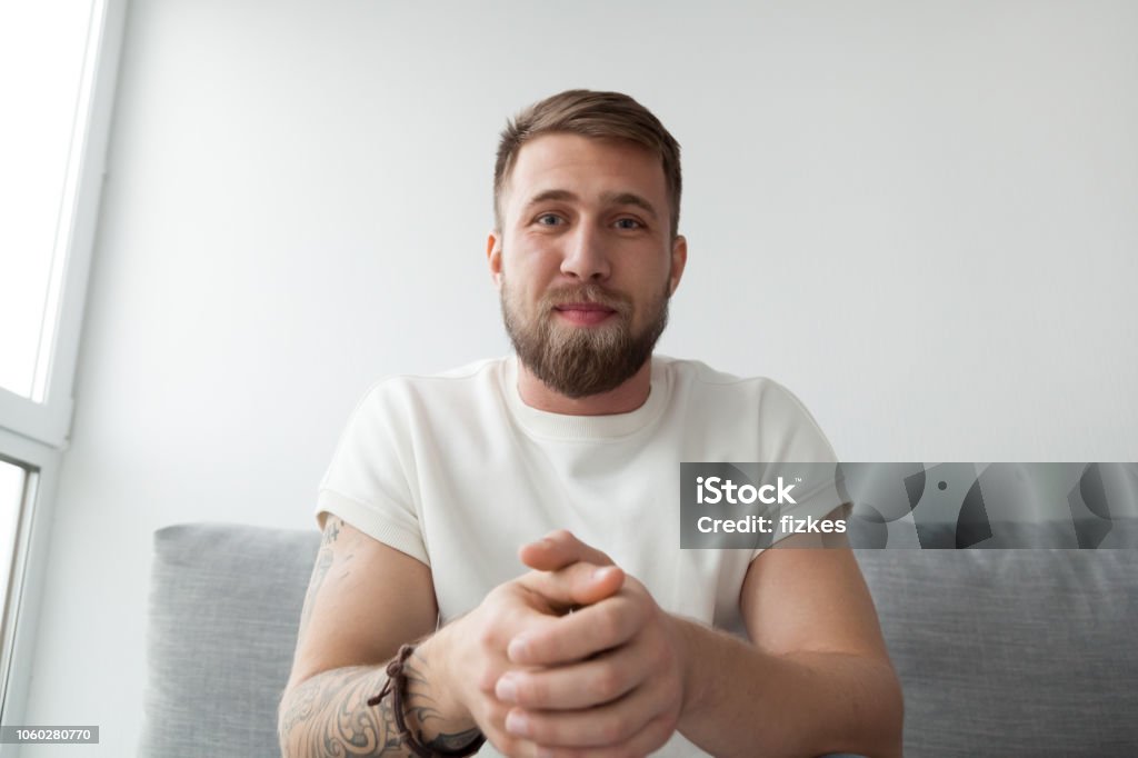 Millennial man making video call on laptop Portrait of happy millennial man making video call on laptop sitting on couch at home, young mentor or trainer record online webinar or training, male communicate or broadcast live on computer Men Stock Photo