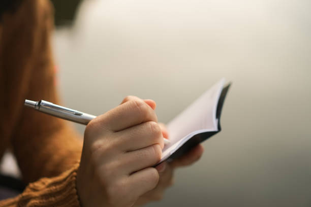 istock Woman hand writing down in small white memo notebook for take a note not to forget or to do list plan for future. 1060341822