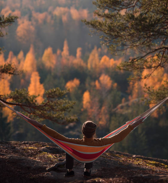 istock A man sits in a hammock and admires the autumn forest. View from the back. 1060347758