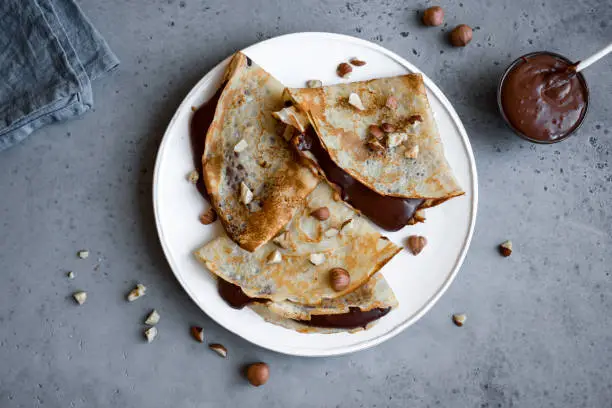 Crepes with chocolate spread and hazelnuts. Homemade thin crepes for breakfast or dessert.