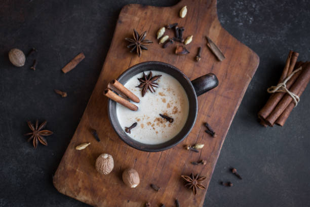 Masala Chai Tea Traditional indian masala chai tea in ceramic cup with ingredients. Spicy black tea with milk on rustic dark background, top view. Cardamom stock pictures, royalty-free photos & images