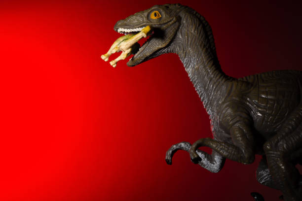 istock Deinonychus biting a smaller dinosaur with red light in dark 1060356338