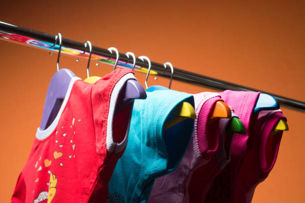 istock Hangers with colourful clothes on orange background. 1060356446