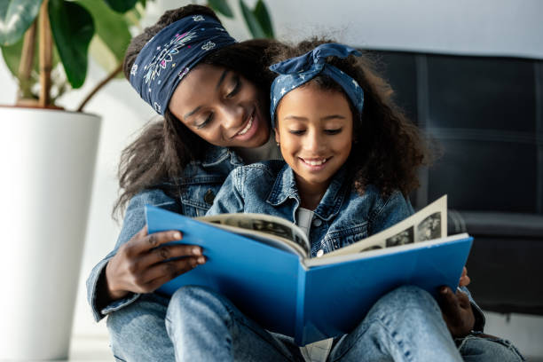 portrait of smiling african american mother and daughter looking at family photo album at home portrait of smiling african american mother and daughter looking at family photo album at home scrapbook stock pictures, royalty-free photos & images