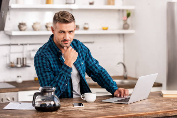 istock handsome man in checkered shirt using laptop and looking at camera 1060361510