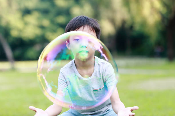 istock Cheerful toddler boy playing with soap bubbles in park 1060365800