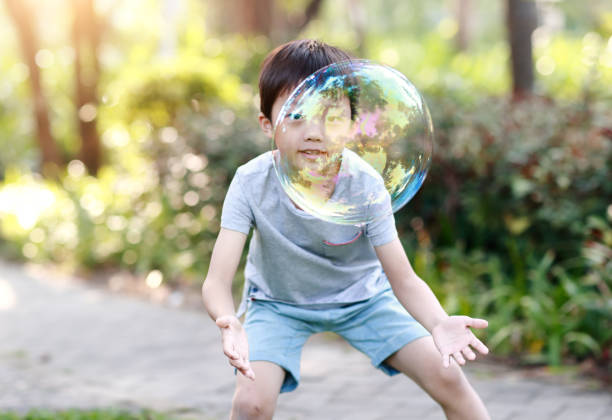 istock Cheerful toddler boy playing with soap bubbles in park 1060365850