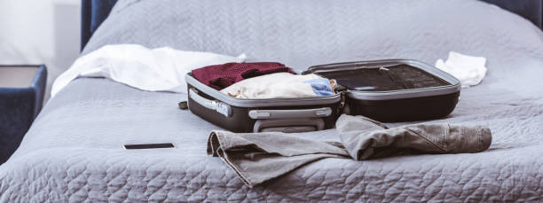 istock wheeled bag, clothes and smartphone on bed at home 1060366054