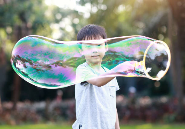 陽気な幼児用ボーイズと遊ぶ石鹸の泡に公園 - bubble wand child blowing asian ethnicity ストックフォトと画像