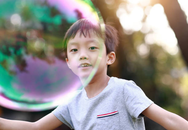 istock Cheerful toddler boy playing with soap bubbles in park 1060377036