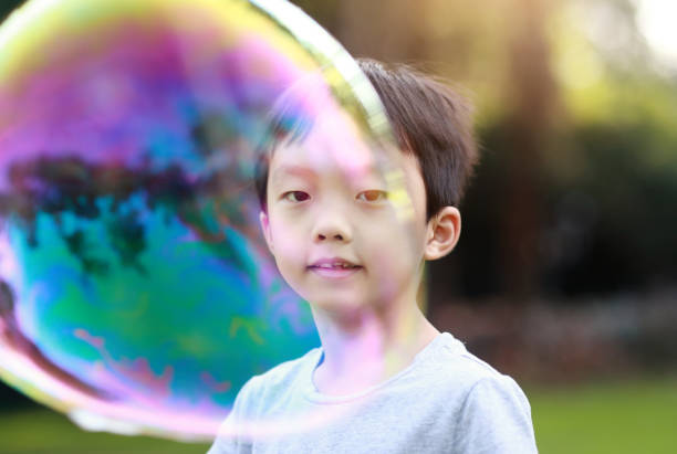 istock Cheerful toddler boy playing with soap bubbles in park 1060377062