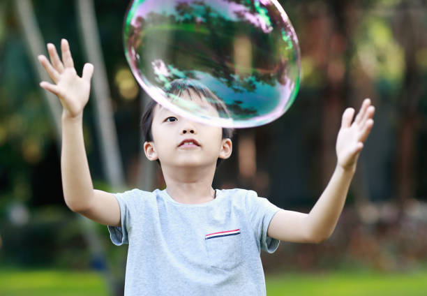 istock Cheerful toddler boy playing with soap bubbles in park 1060377064