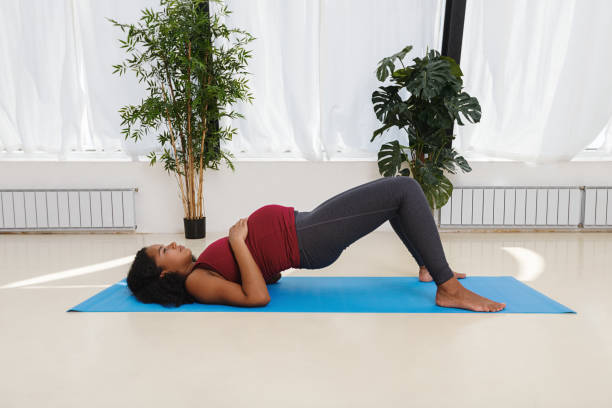 mujer joven embarazada haciendo ejercicio en la estera de yoga en studio - human pregnancy yoga exercising prenatal care fotografías e imágenes de stock