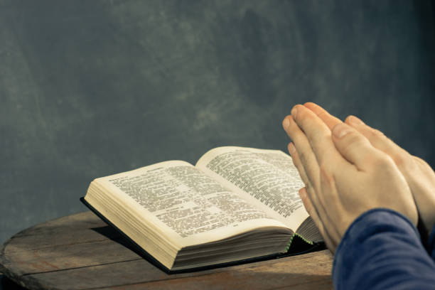 istock Young man sitting at a table reading the Holy Bible 1060381002