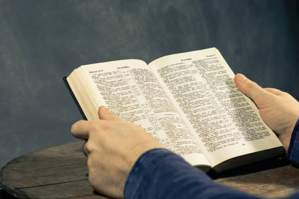 istock Young man sitting at a table reading the Holy Bible 1060381196