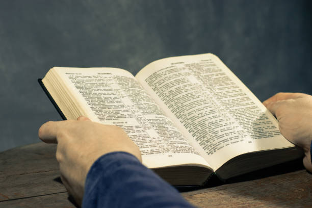 istock Young man sitting at a table reading the Holy Bible 1060383912