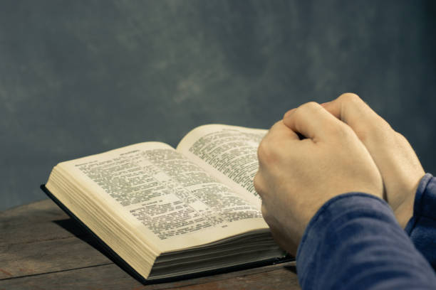 istock Young man sitting at a table reading the Holy Bible 1060383958
