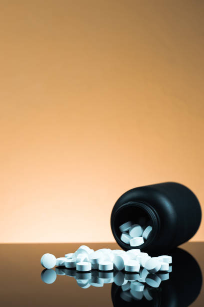 istock Black Bottle for pills on a black glass table. Beautiful yellow  background. 1060390870