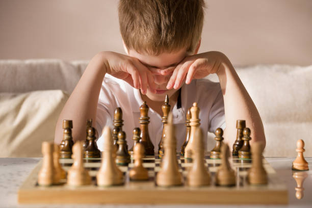 istock Boy playing chess in the room. Little clever boy concentrated and thinking while playing chess at home. 1060396512