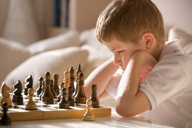 istock Boy playing chess in the room. Little clever boy concentrated and thinking while playing chess at home. 1060396586