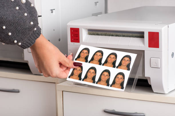 Just printed passport photos exiting a printer Set of just printed passport photos of a young woman exiting the printer with the hand of a woman reaching for the sheet in a close up view passport photos stock pictures, royalty-free photos & images