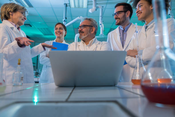 istock Below view of team of happy scientists talking while using laptop in laboratory. 1060402558