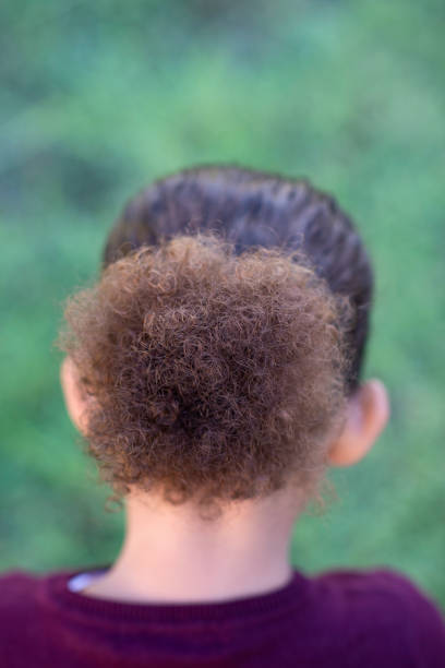 Portrait of little girl with the elegant simple hair bun. Beautiful hairstyle, charm. Back view.
