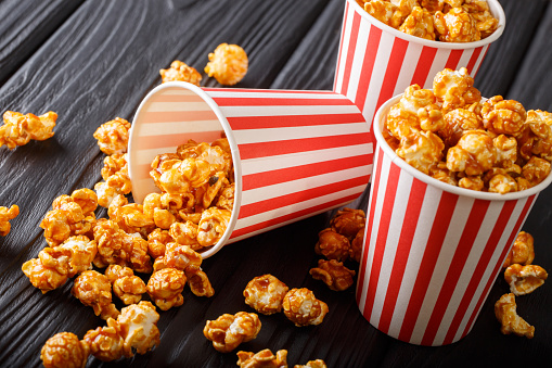 Boxes with wweet caramel popcorn, black background, Snack for cinema closeup. Horizontal
