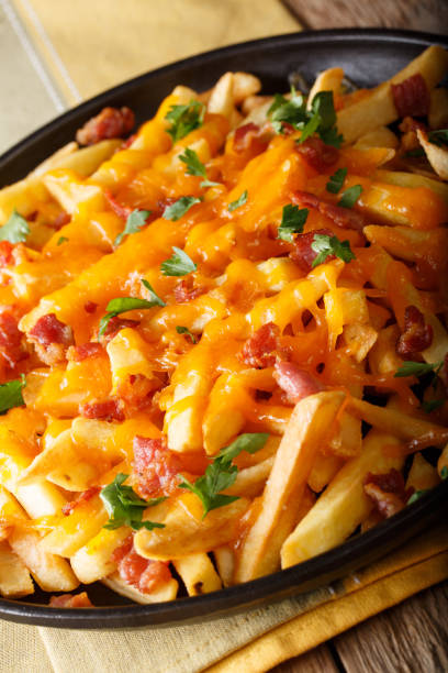 istock French fries with cheddar cheese, bacon and herbs close-up. vertical 1060407162