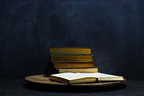 istock One open old book on a round wooden table. Beautiful dark background. 1060411750
