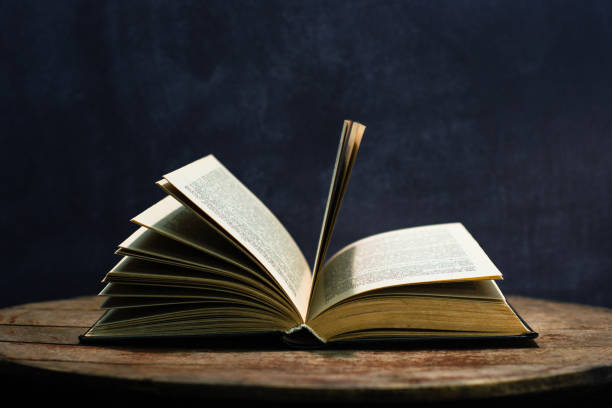istock One open old book on a round wooden table. Beautiful dark background. 1060412400