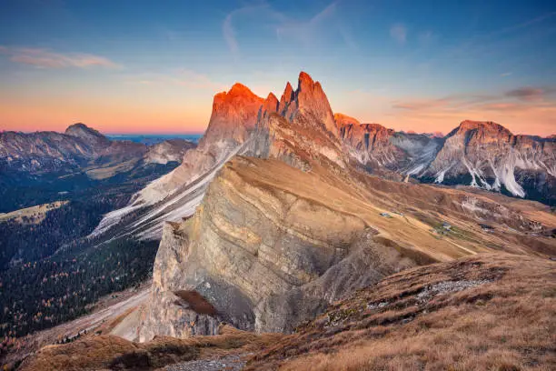Landscape image of famous Dolomites mountain peaks glowing in beautiful golden evening light at sunset in autumn, South Tyrol, Italy.