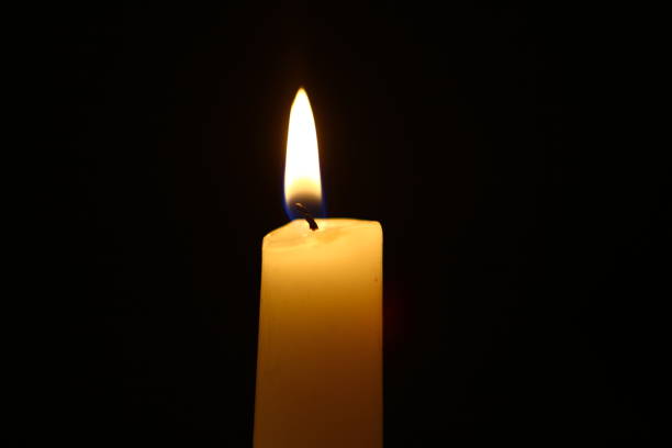 istock standing paraffin burning candle with vivid fire on heavy black background. 1060414288