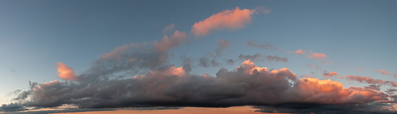 Panoramic photo of blue sky and dramatic clouds at sunset. Sunset light on the clouds.