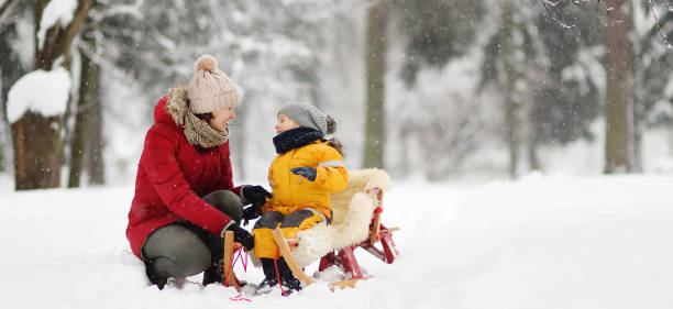 madre / tata parlano con il bambino piccolo durante lo slittino nel parco invernale - cold discussion outdoors snow foto e immagini stock