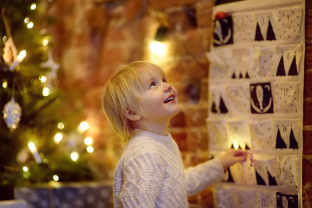 niño feliz lleva dulce de calendario de adviento en la nochebuena - advent calendar advent christmas childhood fotografías e imágenes de stock