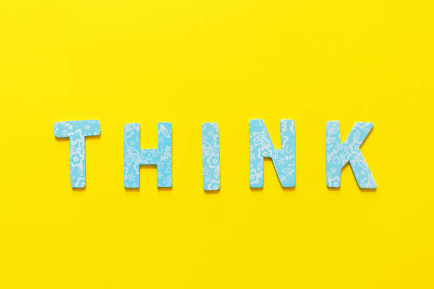 Word THINK  made out of small blue  letter on yellow background, flat lay