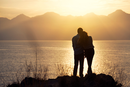 Silhouette of young couple embracing in front of sea during sunset, Antalya, Turkey